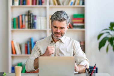 Sinirli bir adam, bilgisayarın başında otururken yüzünün gergin ifadesiyle bir jest yapar.