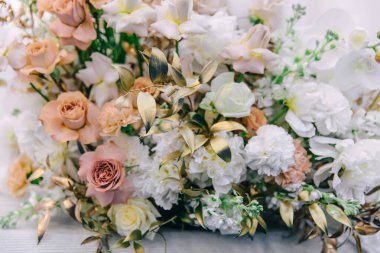 Masada yeni evliler için bir buket orkide, gül ve şakayık var. Buket altın dallarla tamamlanır..