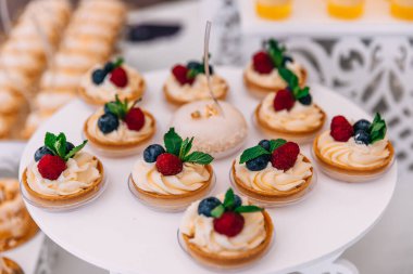 Ahududu, nane yaprağı ve yaban mersiniyle süslenmiş kremalı sepetler. düğün.