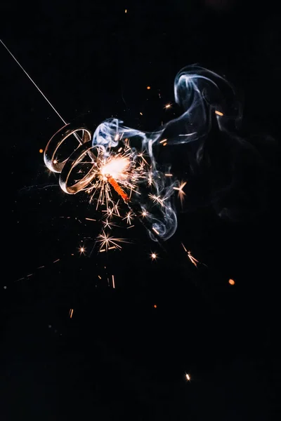 Wedding rings with sparklers on a black background in smoke