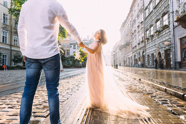 ドレスを着た幸せな女性と花の花束は日没を背景に腕の後ろに男を保持します — ストック写真