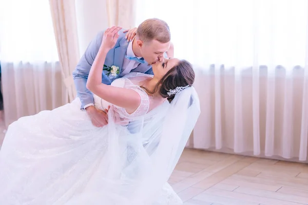 bride and her husband dance and kiss together their first wedding dance in a restaurant