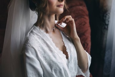 Parlak pırlanta kolyeli ve cüppeli genç bir kadın düğüne hazırlanıyor. Sabah gelin..