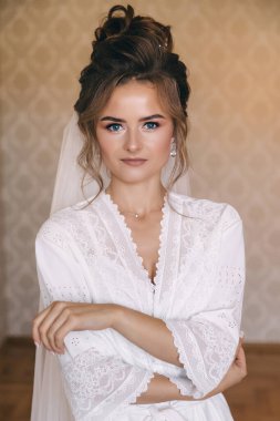 Beyaz cübbeli mükemmel gelin. Güzel saçlar ve temiz, yumuşak bir ten. Tören için hazırlıklar.