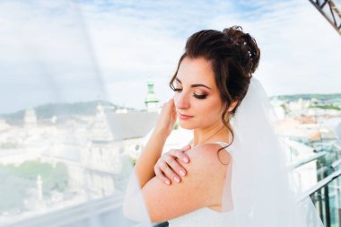 Şehrin panoramasının arka planında güzel bir makyajı olan bir gelinin yakın çekimi.