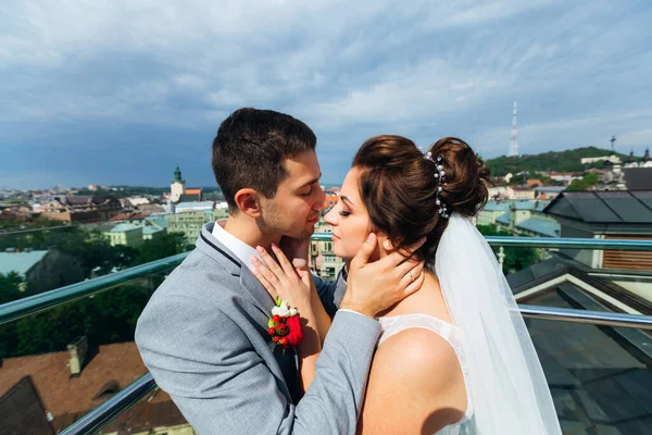 Newlyweds Csók Erkélyen Csodálatos Kilátás Nyílik Városra — Stock Fotó