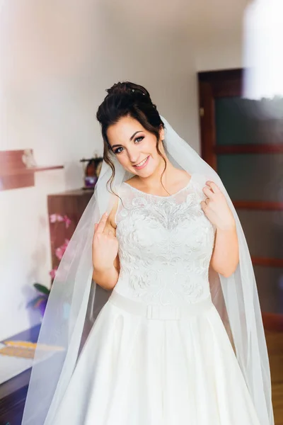 bride in white dress and bridal veil looks at the camera and smiles