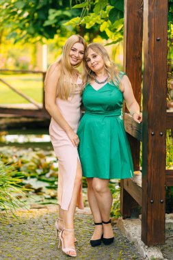 charming blonde lady smiling while standing next to her mother and hugging her. Holidays in nature