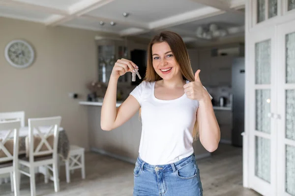 Young Smiling Girl Holding Keys New Real Estate Showing Thumb — стоковое фото