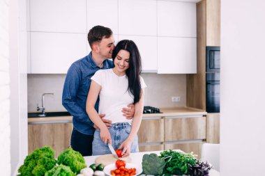 Mutlu çift evde mutfakta dikilip sebze salatası hazırlarken. Vejetaryenler sebze doğruyor. Akşam yemeği için hazırlanıyorlar. .