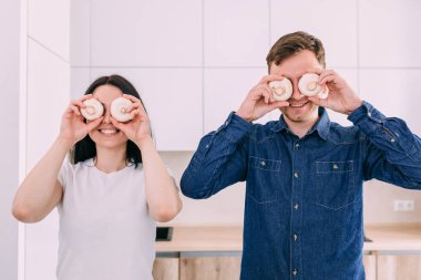 Genç evli çift mutfakta kahvaltı hazırlıyor gözlerini mantarla kapayıp gülüyorlar..