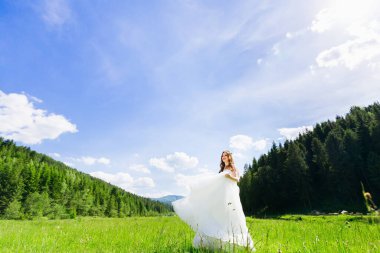 Beyaz gelinlikli gelin yaz danslarında çayırda yürüyor..