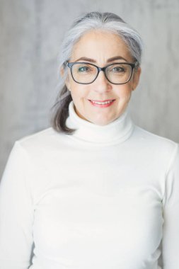 Sağlıklı yaşlılar ve 60 'ların mutlu yaşlı büyükannesi hakkında iyimser bir şekilde gülümseyen olgun gri saçlı kadının yakın plan portresi..