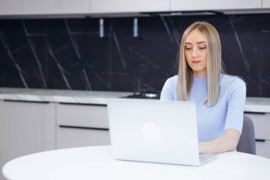 Beautiful woman works with a laptop, serious girl writes a report, distance learning. Modern technology concept
