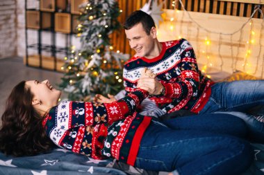 Birbirine aşık çiftler Noel ağacının yanındaki yatakta eğleniyorlar. Gülümse.