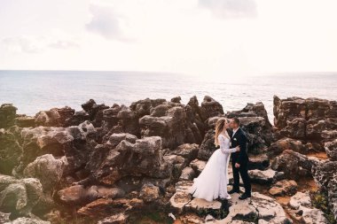 Birbirlerinin kollarında yeni evlilerin profili. Okyanusun kayalık kıyısı ve uçsuz bucaksız okyanus.