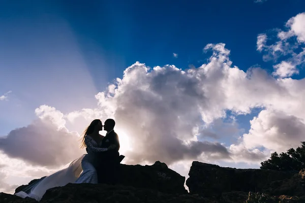 Novomanželé Zavřeli Oči Sedí Kamenech Pozadí Modré Oblohy Mraků — Stock fotografie