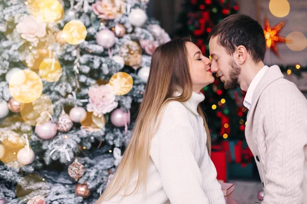 在圣诞树背景下恋爱的夫妻的简况 男人和女孩闭上眼睛 女孩吻男人 — 图库照片