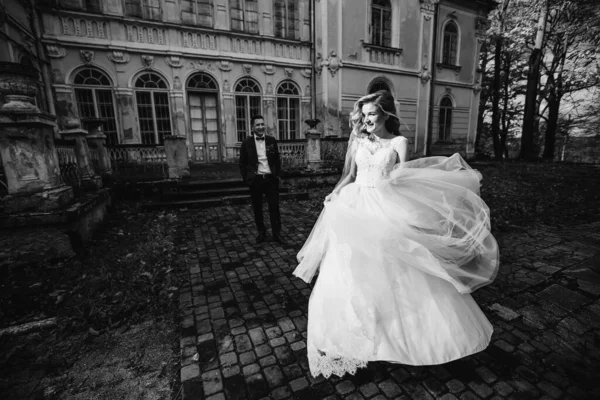 Nevěsta Svatebních Šatech Běží Chodníku Ženich Pozadí Budovy Drží Ruce — Stock fotografie
