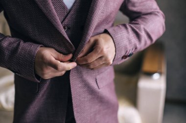 Damat ceketine düğme takıyor, törenden önce damadın sabahını..