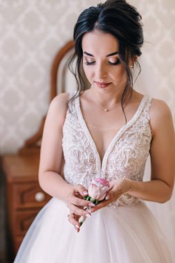 Beyaz elbiseli mutlu gelin, elinde yaka çiçeğiyle damadı bekliyor..