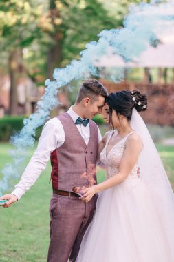 Ellerinde sigara olan yeni evliler doğanın arka planında sarılıyorlar..