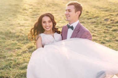 Güzel bir çift düğün günlerinde güneşli bir günde doğada eğleniyorlar. Damat gelini kollarına alır ve onunla dans eder..