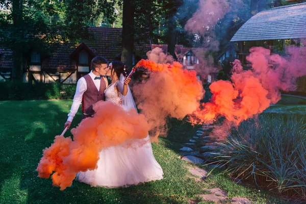 Piękni Nowożeńcy Stoją Lesie Trzymają Rękach Kolorowe Bomby Dymne — Zdjęcie stockowe