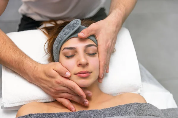Facial massage. Close-up of young woman getting massage at spa salon.Spa care for skin and body. Facial beauty care. Cosmetology.