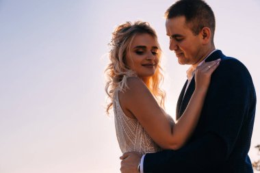 Mavi gökyüzüne karşı mutlu, genç bir çift. Düşük açı. Balayı gezisi