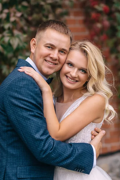 Gelin ve damat şehrin ıssız caddelerinde yürüyor. Yeni evliler yakınlarda duruyor ve güzel bir evin turuncu duvarının yanında sarılıyorlar..