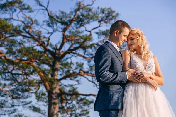 山の中で美しい結婚式のカップル 白いドレスの花嫁と木と青空を背景にスタイリッシュな新郎 — ストック写真