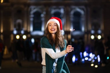 Parlak makyajlı gülümseyen kız gece havai fişeklerle dışarıda. Bu olayı kutlayan genç bayan yeni yıla yaklaşıyor.