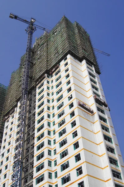 Edifício branco em construção com um guindaste de torre — Fotografia de Stock