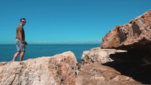Un hombre salta sobre rocas sobre un desfiladero cerca del Mar Negro — Vídeo de stock