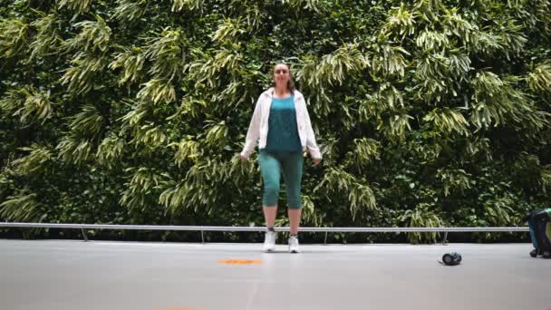 Ragazza che balla allegramente all'aeroporto contro un muro di vegetazione verde — Video Stock