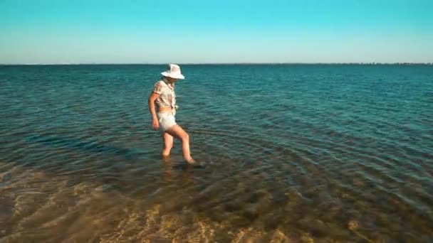 女の子が湖の中の粘土の上を歩く — ストック動画