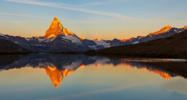 Beautiful sunset colors and cloudscape in the Swiss Alps in summer, with Matterhorn reflection in a lake