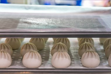 Raftaki tepside birçok somun ekmek hamuru Çin ya da Asya yemeği (buharda pişirilmiş çörek).