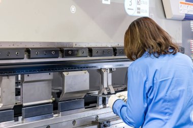 Close up technician hand hold metal flat sheet insert between punch and v die of the semi automatic cnc hydraulic press brake or bending machine  during folding forming.