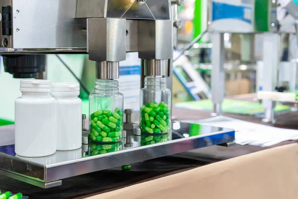 Üretim sırasında otomatik ilaç kapsülü şişesi doldurma ve sayma makinesinin başlığının altında temiz plastik şişeyle beyazı kapat