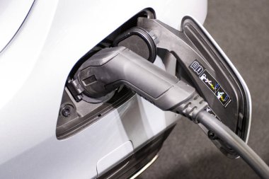 Aracın aküsünü şarj etmek yeni otomotiv yenilikleri şarj edilen elektrikli bir arabaya takılan güç kaynağı, enerji yeniliği kavramı..