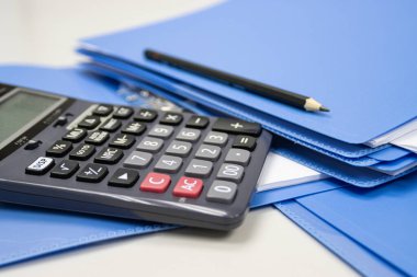 Çalışma ofisindeki masada dosya dizini bulunan hesap makinesi, iş ve maliyet ve finansal planlama hesaplayıcısını kavramsallaştırır