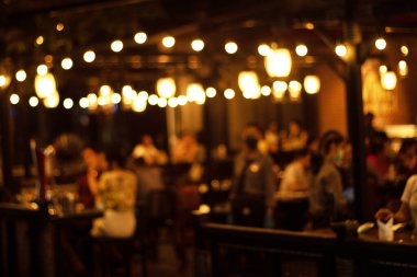 Restauranttaki bir çok insan gece mutlu mesut yemek yer ve eğlenir.