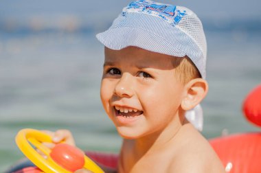 Yaz günü sahilde gülümseyen küçük bir çocuğun portresi.