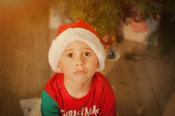 Kleine Jongen Met Een Somber Gezicht Onder Een Kerstboom Thuis — Stockfoto