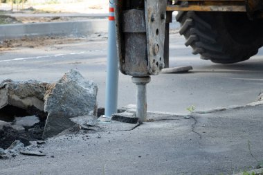 Yol tamiri. Eski bir asfalt katmanının hidrolik çekiçle çıkarılması. Asfaltın yeniden inşası.