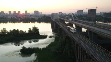 Dinyeper Nehri üzerindeki Darnitsky Köprüsü. Ukrayna şehri Kiev. Drone 'un videosu. Tren köprüden geçtiğinde, demiryolu köprüsünün kenarındaki açıklık.