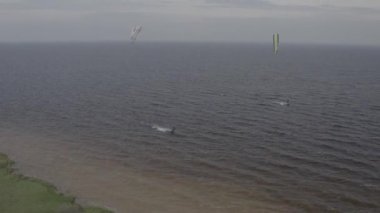 Atletler uçurtma sörfüne biner. Kiev Denizi. Yaz. Rüzgarlı bir hava. Rekabet. Renkli yelkenler. Havadan. Ukrayna. Kyiv.