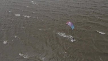 Atletler uçurtma sörfüne biner. Kiev Denizi. Yaz. Rüzgarlı bir hava. Rekabet. Renkli yelkenler. Havadan. Ukrayna. Kyiv.